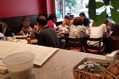 Customers dining inside Wa Lung Kitchen, enjoying meals in a cozy, casual atmosphere with red walls and a welcoming ambiance.